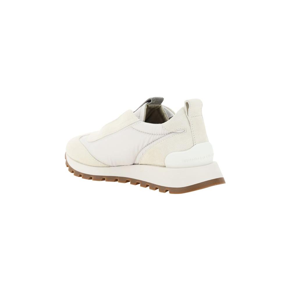 Side view of Brunello Cucinelli sneakers with knurled sole, suede details, and embossed monogram on heel.