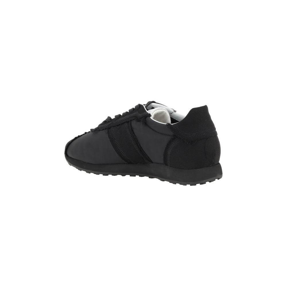 The Row Moveo Sneakers featuring lace-up closure, round toe, and strappy accent with slanted bands in black, minimalist design.