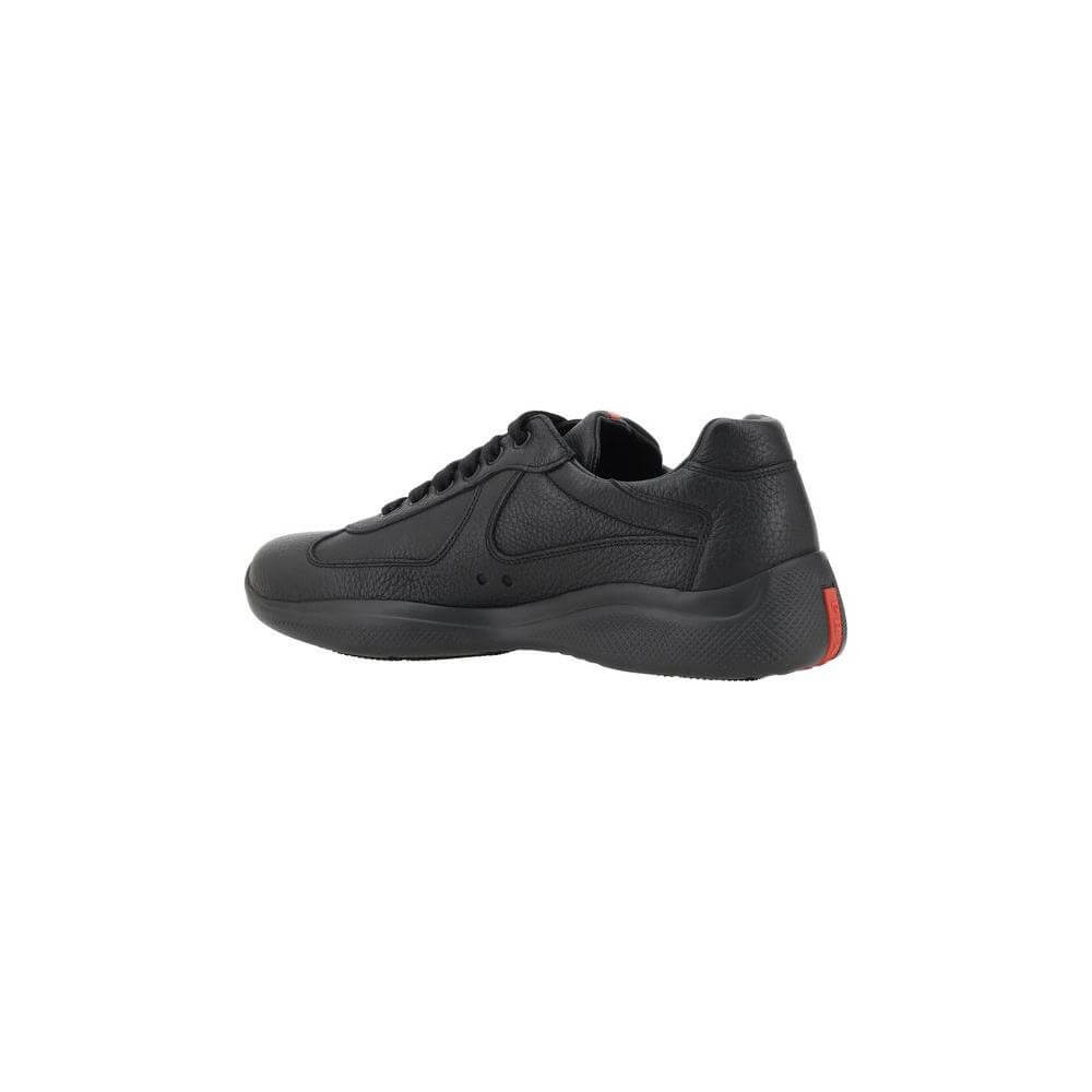 Prada black leather sneakers with sleek design, grained texture, lace-up closure, round toe, and textured sole. Iconic monogram patch.
