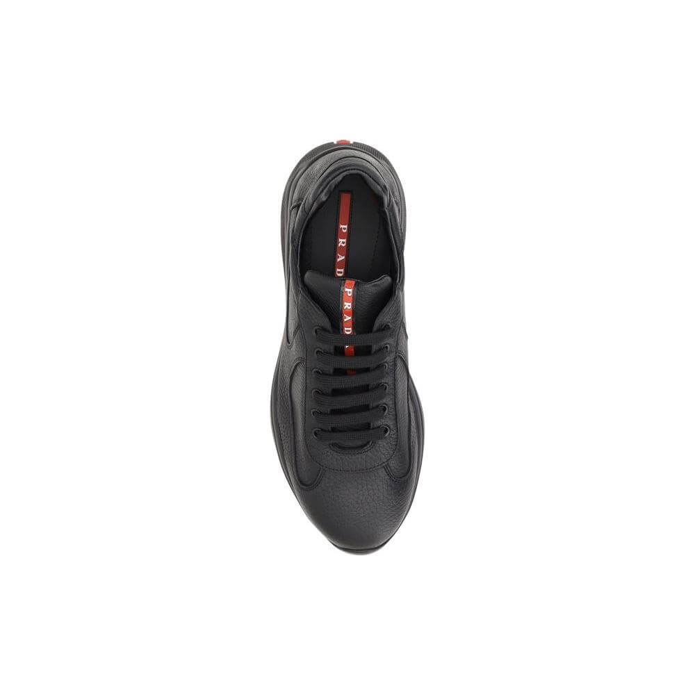 Top view of black Prada leather sneaker with grained texture, lace-up closure, and iconic monogram patch on the tongue.