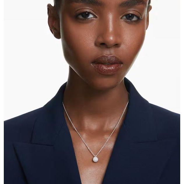 Woman wearing Swarovski necklace with a round pendant, showcasing elegant design and style.