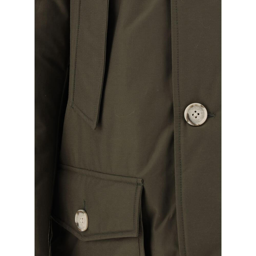 Close-up of Woolrich Green Cotton Parka with button details and front pockets, featuring the iconic brand patch on neckline and padded design.