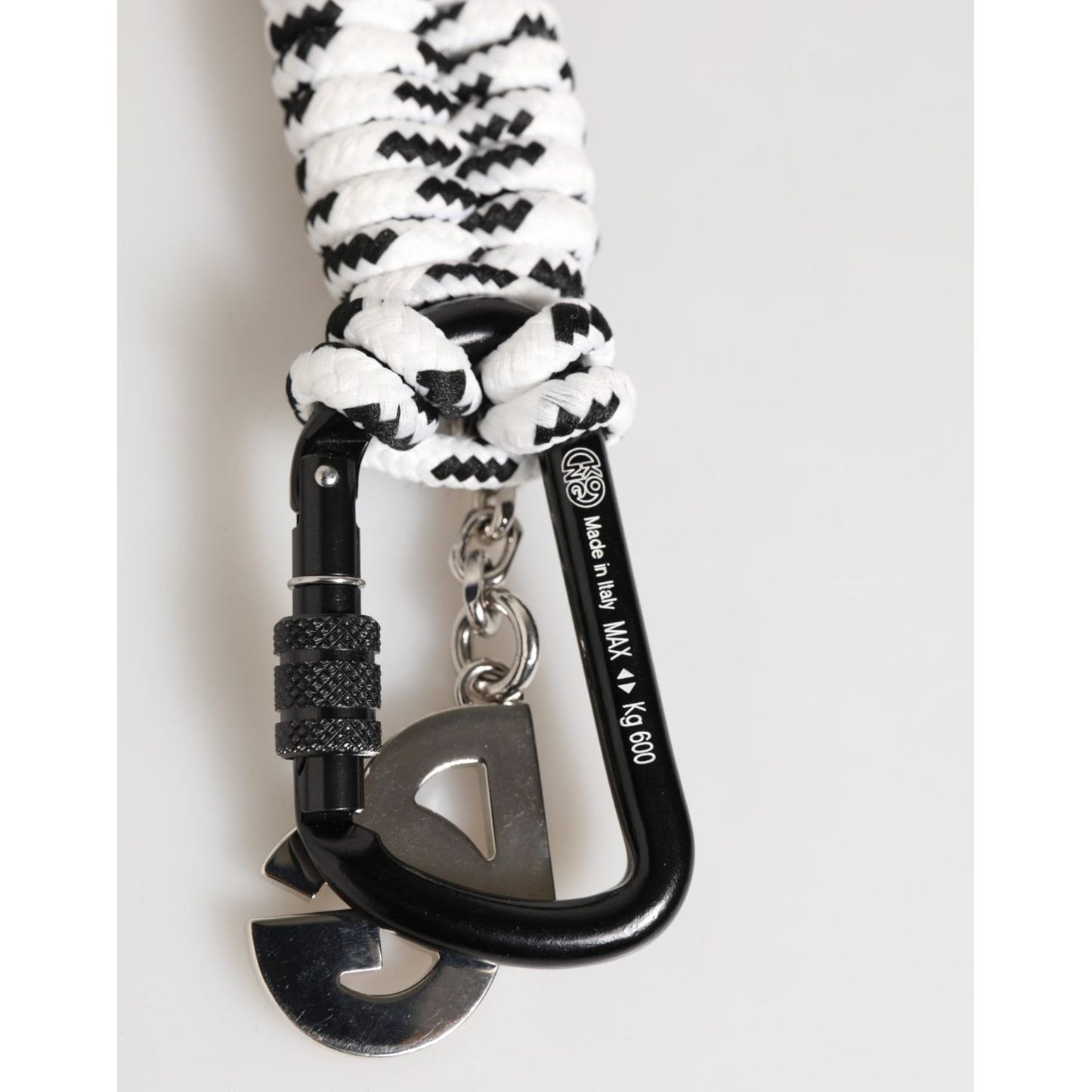 Black carabiner clip with white and black woven rope and metal attachments on a neutral background.