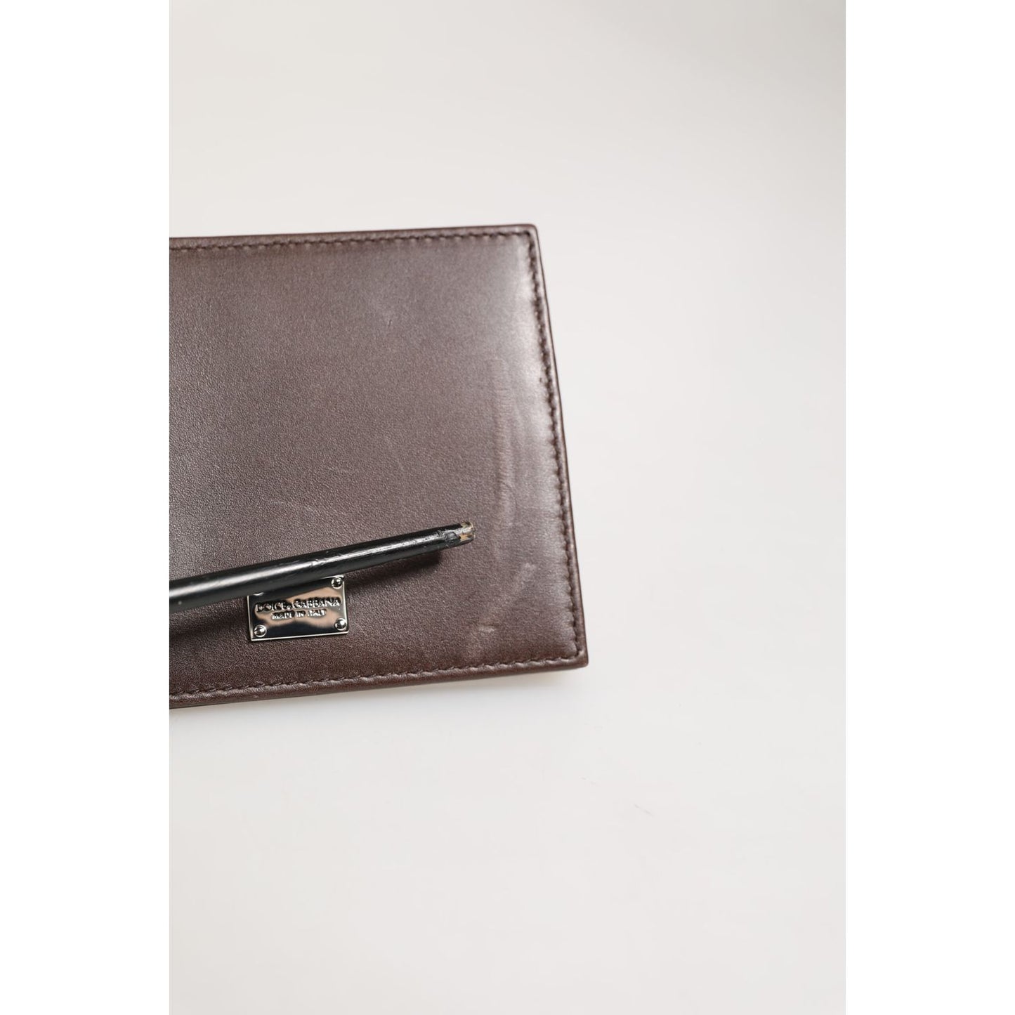 Dolce & Gabbana Brown Leather DG Logo Engrave Bifold Card Holder Wallet with engraved DG logo and pen on top.