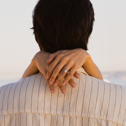 Elegant embrace showcasing a diamond ring on hands around a partner.