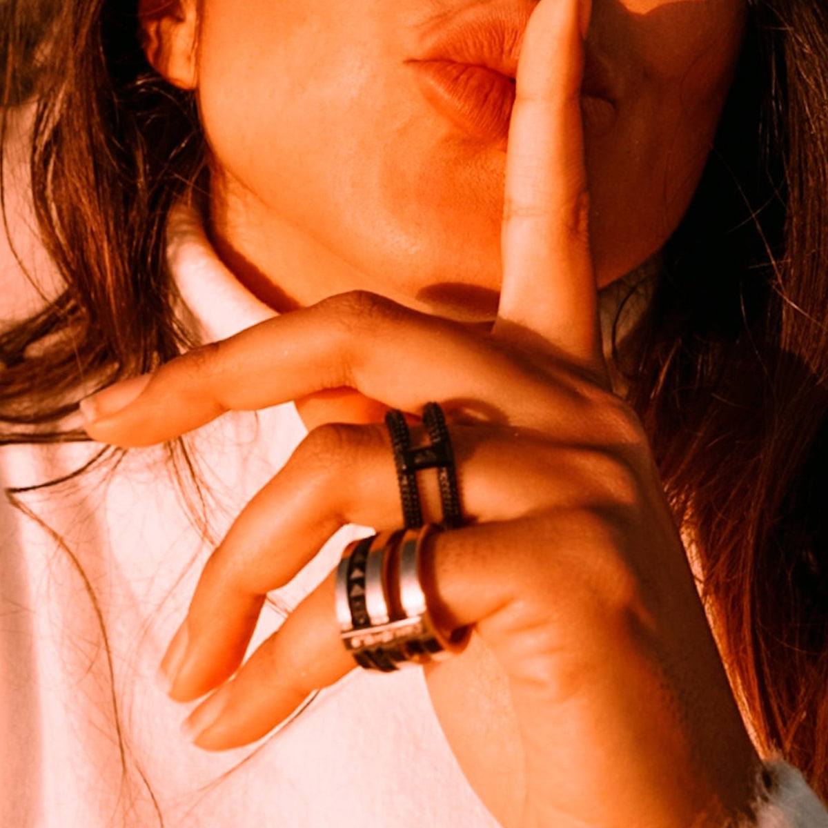 Woman wearing AN JEWELS JEWELRY Mod. AR.R2NS02BK-8 rings, making a shushing gesture with her finger on her lips.
