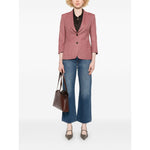 Model wearing Mother Jeans Blue with indigo blue, whiskering effect, and five pockets paired with a brown blazer and holding a handbag.