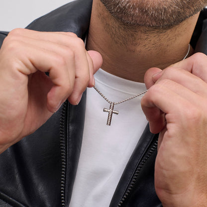 Person wearing cross pendant necklace, focusing on jewelry detail