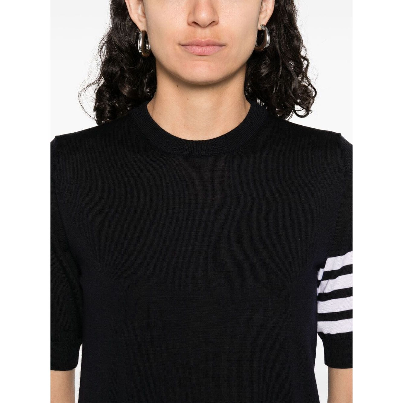 Navy blue Thom Browne sweaters with short sleeves, crew neck, signature grosgrain loop tab, and 4Bar wool design, side view.
